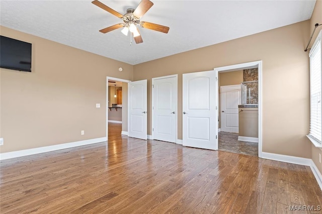 unfurnished bedroom featuring multiple windows, ceiling fan, and hardwood / wood-style flooring