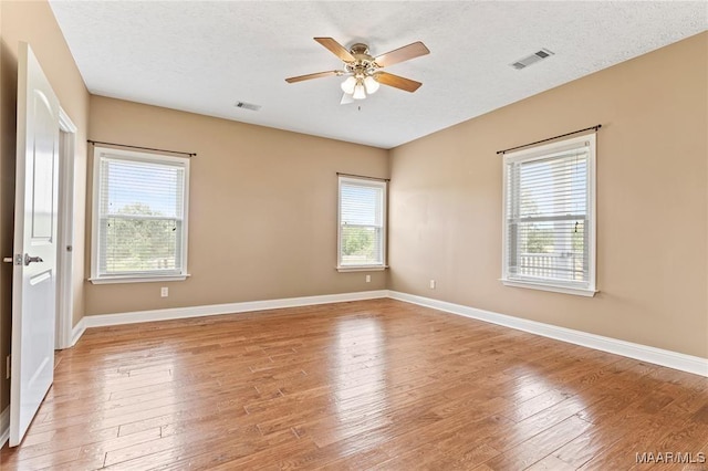 empty room featuring ceiling fan, light hardwood / wood-style floors, and a textured ceiling