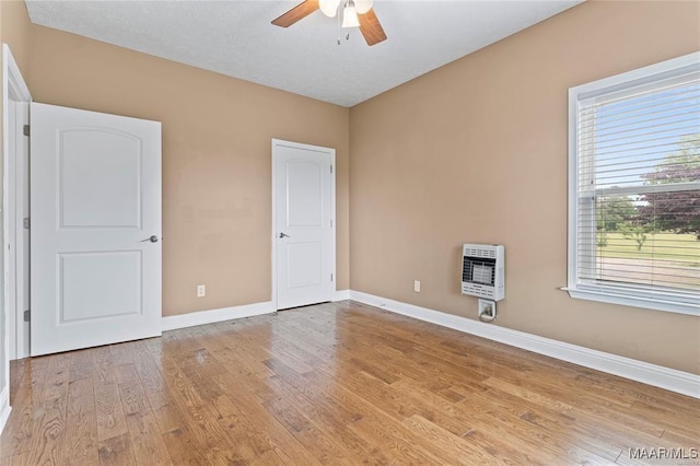 interior space with heating unit, ceiling fan, a textured ceiling, and light wood-type flooring