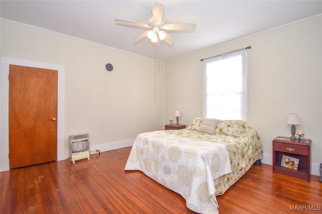 bedroom featuring ceiling fan, dark hardwood / wood-style flooring, crown molding, and heating unit