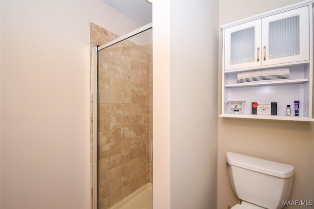 bathroom with a shower with shower door and toilet