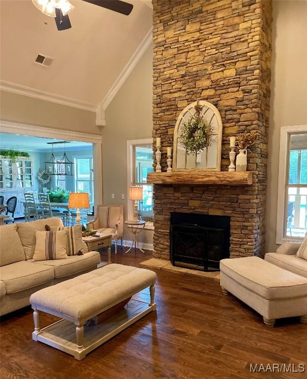 living room with dark hardwood / wood-style flooring, high vaulted ceiling, a healthy amount of sunlight, and a stone fireplace