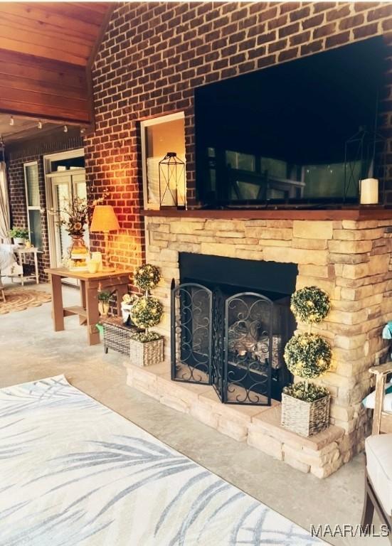 living room with concrete floors, exterior fireplace, wooden ceiling, and brick wall