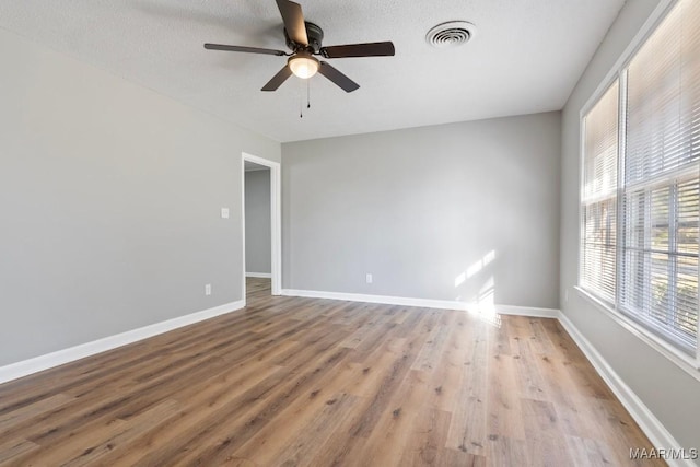 empty room with a textured ceiling, light hardwood / wood-style flooring, and ceiling fan