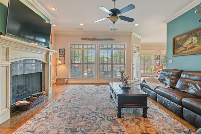 living room with hardwood / wood-style flooring, a fireplace, ceiling fan, and crown molding