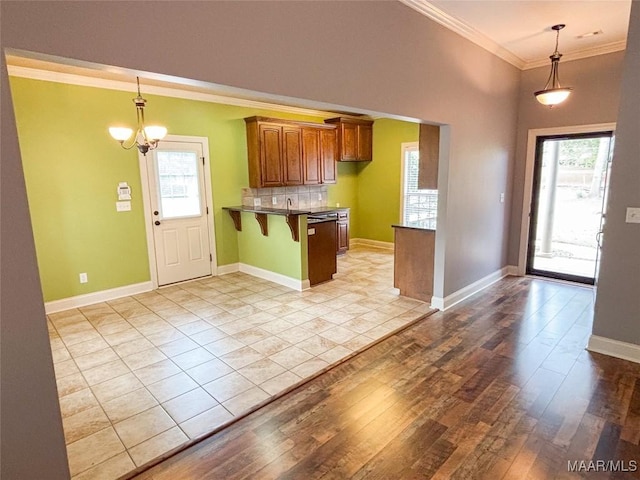 kitchen with hanging light fixtures, a kitchen breakfast bar, a notable chandelier, light hardwood / wood-style floors, and ornamental molding