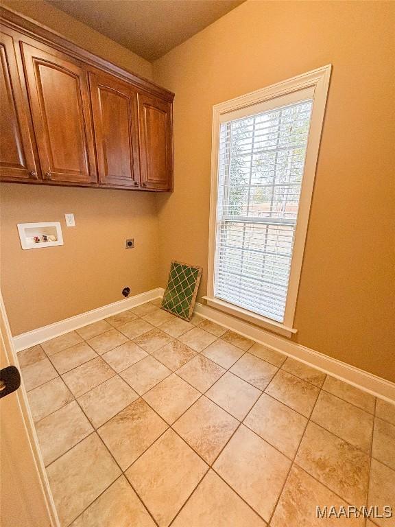 clothes washing area with hookup for an electric dryer, light tile patterned flooring, cabinets, and hookup for a washing machine