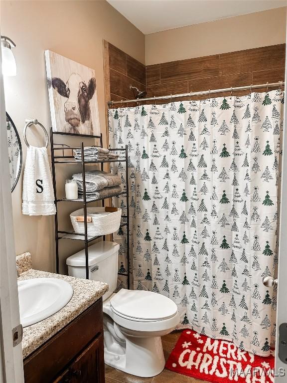 bathroom with curtained shower, vanity, and toilet