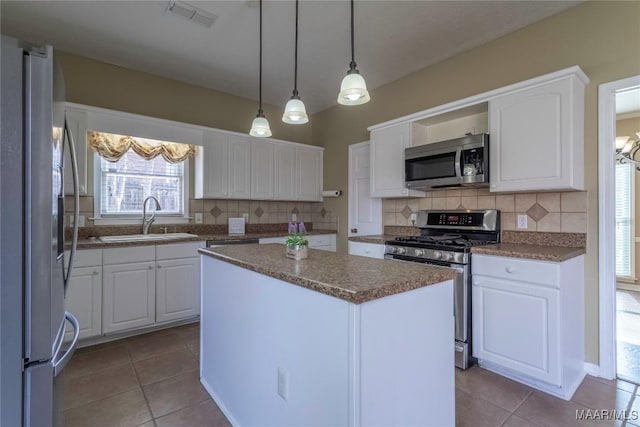 kitchen with sink, appliances with stainless steel finishes, tasteful backsplash, a kitchen island, and white cabinetry