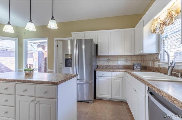 kitchen with sink, stainless steel appliances, backsplash, decorative light fixtures, and white cabinets