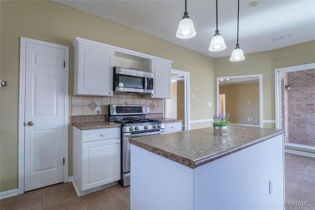 kitchen featuring white cabinetry, light tile patterned flooring, decorative light fixtures, a kitchen island, and appliances with stainless steel finishes