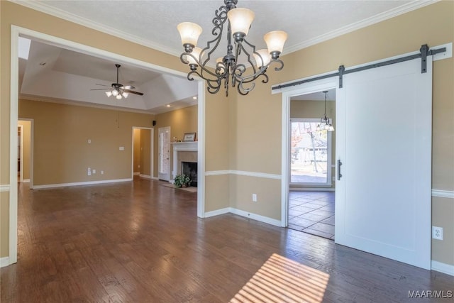 interior space featuring a tray ceiling, a barn door, dark wood-type flooring, and ornamental molding