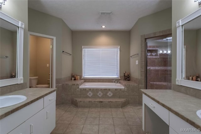 bathroom featuring tiled bath, tile patterned flooring, vanity, and toilet