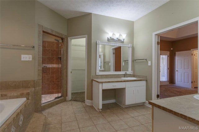 bathroom with tile patterned floors, vanity, separate shower and tub, and a textured ceiling