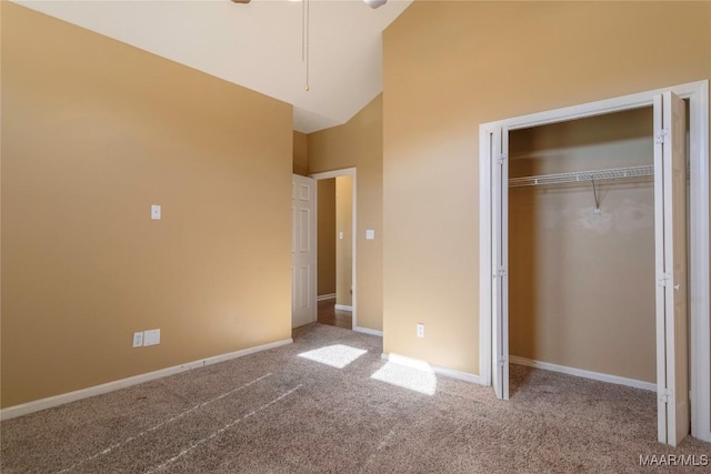 unfurnished bedroom featuring carpet flooring, high vaulted ceiling, and a closet