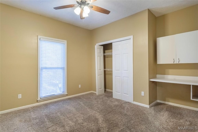 unfurnished bedroom featuring ceiling fan, a closet, carpet, and built in desk