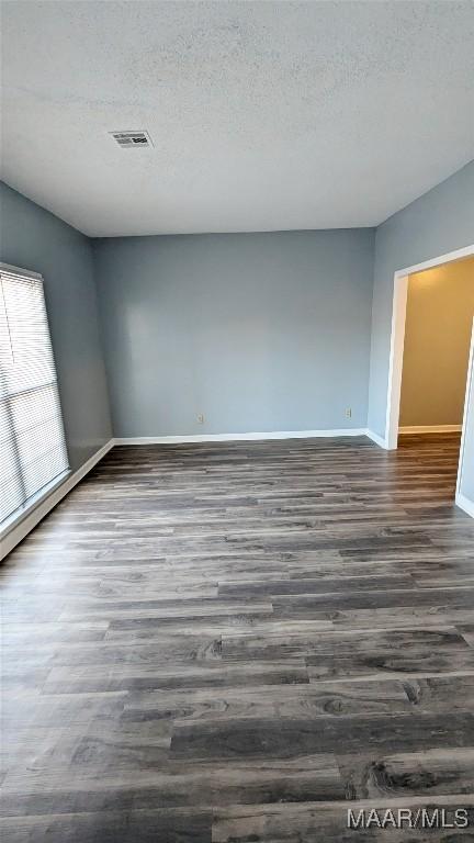 unfurnished room featuring a textured ceiling and dark hardwood / wood-style floors