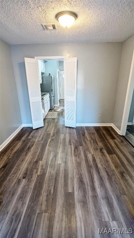 spare room featuring dark hardwood / wood-style floors and a textured ceiling