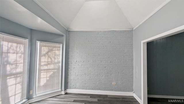 empty room featuring hardwood / wood-style floors, brick wall, lofted ceiling, and ornamental molding