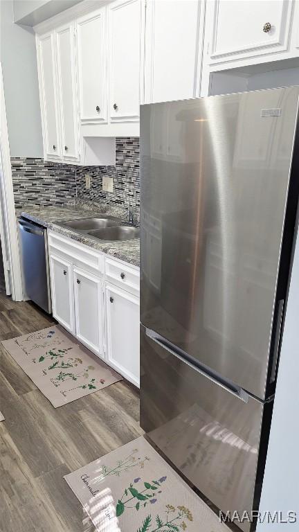 kitchen with backsplash, dark wood-type flooring, sink, appliances with stainless steel finishes, and white cabinetry