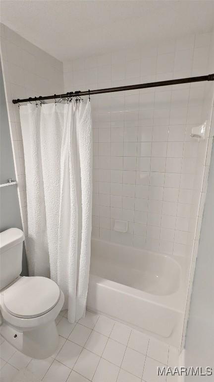 bathroom with tile patterned floors, shower / bath combo with shower curtain, and toilet