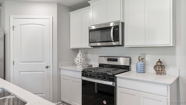 kitchen featuring light stone countertops, appliances with stainless steel finishes, and white cabinetry