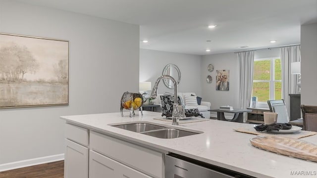 kitchen featuring white cabinetry, sink, dishwasher, light stone countertops, and dark hardwood / wood-style floors