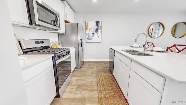 kitchen featuring appliances with stainless steel finishes, sink, light hardwood / wood-style flooring, white cabinets, and an island with sink