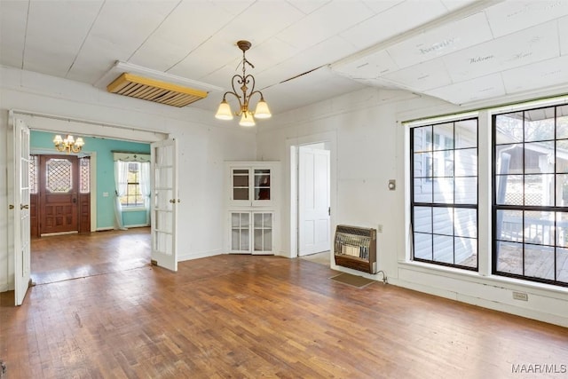 unfurnished living room with heating unit, a chandelier, and wood-type flooring