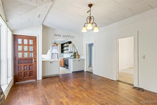 entrance foyer with a chandelier, dark wood-type flooring, and lofted ceiling