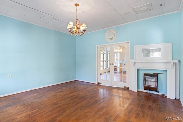 unfurnished living room with an inviting chandelier, french doors, crown molding, a fireplace, and dark hardwood / wood-style flooring