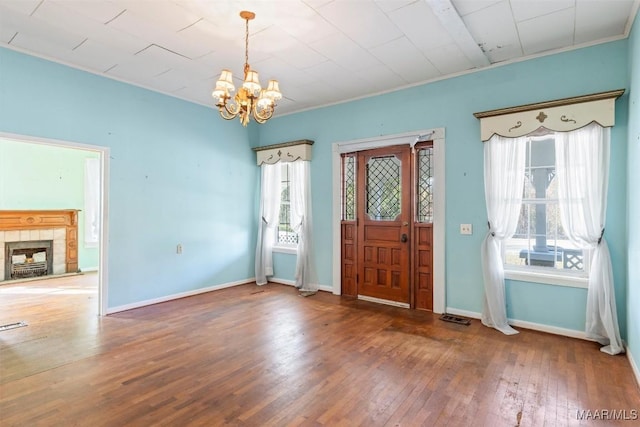 foyer entrance featuring a fireplace, dark hardwood / wood-style flooring, an inviting chandelier, and a healthy amount of sunlight