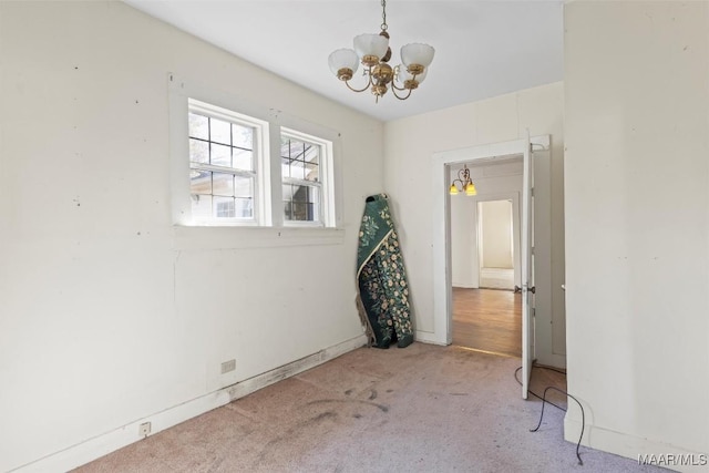 carpeted empty room with a chandelier