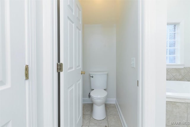 bathroom featuring tiled bath, tile patterned flooring, and toilet