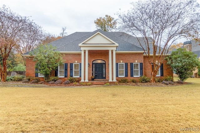 neoclassical home featuring a front lawn