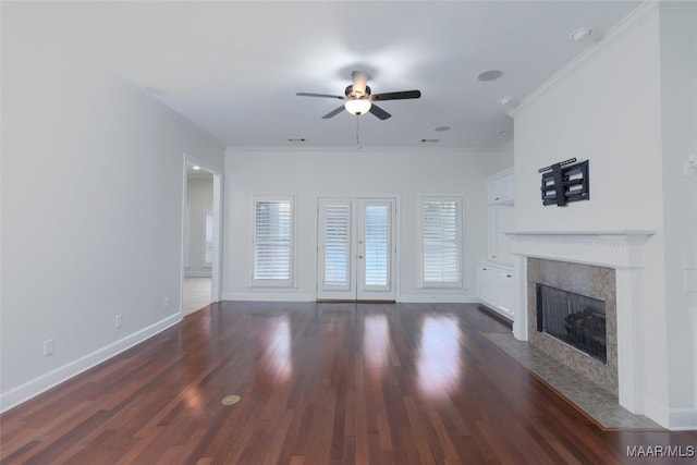 unfurnished living room featuring french doors, ceiling fan, crown molding, dark wood-type flooring, and a fireplace