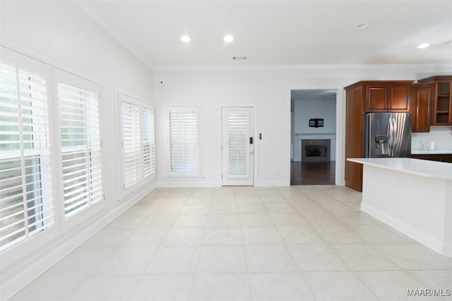 kitchen with crown molding, light tile patterned floors, and stainless steel refrigerator with ice dispenser