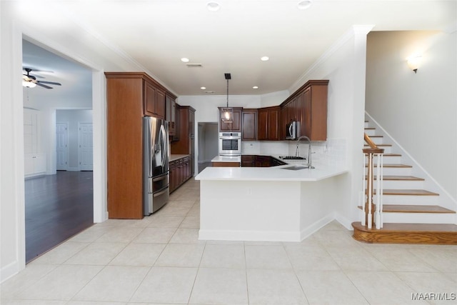 kitchen featuring kitchen peninsula, appliances with stainless steel finishes, ornamental molding, sink, and pendant lighting