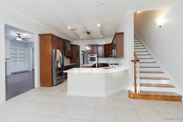 kitchen featuring kitchen peninsula, appliances with stainless steel finishes, tasteful backsplash, sink, and hanging light fixtures