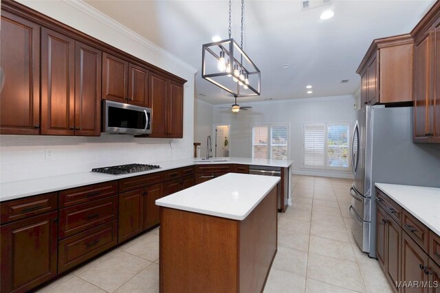 kitchen featuring sink, hanging light fixtures, kitchen peninsula, appliances with stainless steel finishes, and ornamental molding