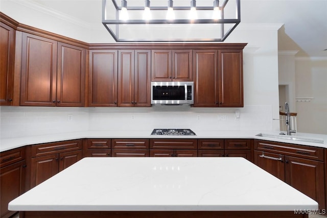 kitchen featuring a center island, crown molding, sink, appliances with stainless steel finishes, and tasteful backsplash