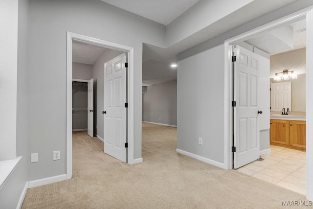 corridor featuring light carpet and sink