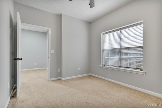 spare room with ceiling fan, light colored carpet, and a textured ceiling