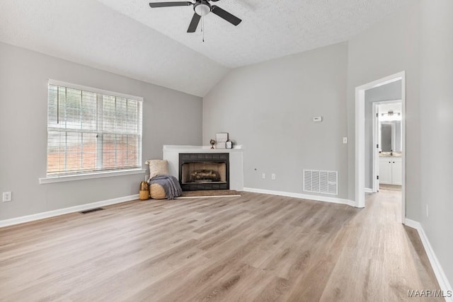 unfurnished living room featuring light wood-type flooring, a textured ceiling, ceiling fan, and lofted ceiling