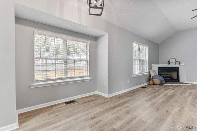 unfurnished living room with ceiling fan, a healthy amount of sunlight, lofted ceiling, and light wood-type flooring