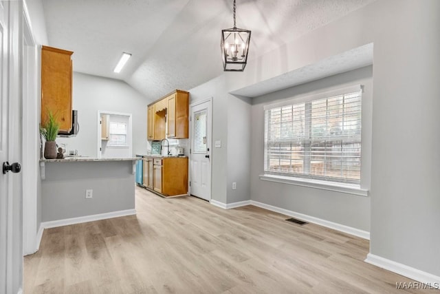 kitchen with hanging light fixtures, light hardwood / wood-style flooring, a notable chandelier, kitchen peninsula, and lofted ceiling