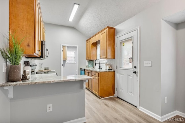 kitchen with a kitchen breakfast bar, light wood-type flooring, light stone counters, a textured ceiling, and range