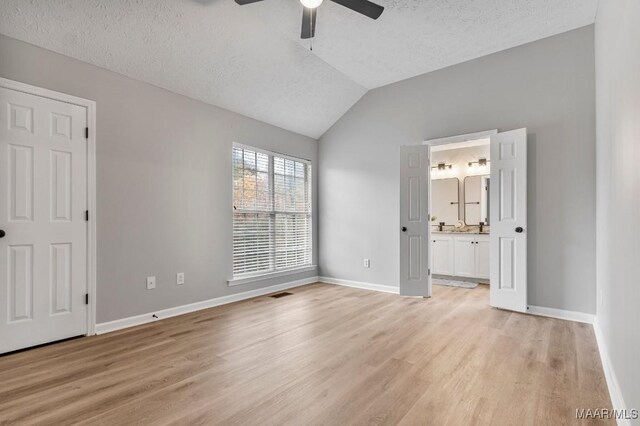 unfurnished bedroom featuring ensuite bath, ceiling fan, lofted ceiling, and light wood-type flooring