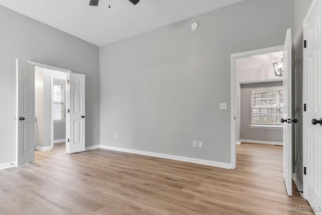 unfurnished room featuring a textured ceiling, light wood-type flooring, and ceiling fan