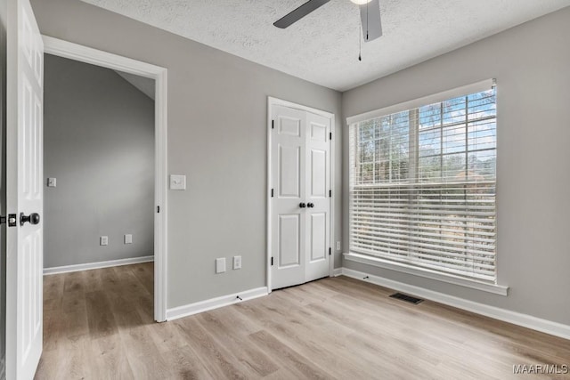 unfurnished bedroom with ceiling fan, a closet, a textured ceiling, and light wood-type flooring